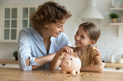 Mother with young child next to piggy bank and coins