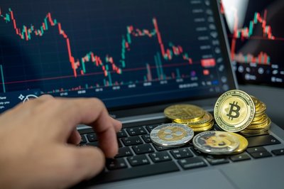 Laptop screen with graph and crypto coins on keyboard