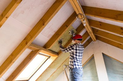 Man on ladder insulating a roof
