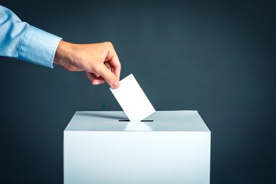 Hand putting voting paper into ballot box